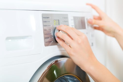 سيدة تقوم بضبط نظام تشغيل غسالة الملابس