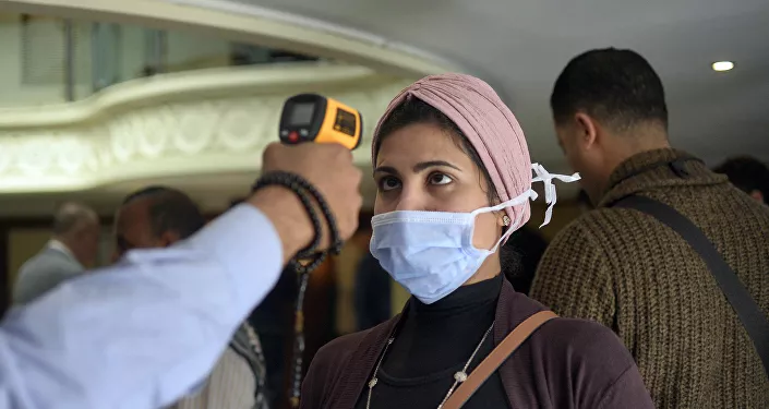 امرأة ترتدي كمامة طبية وتخضع لفحص درجة حرارة جسدها على متن قارب سياحي في مدينة الأقصر بجنوب مصر، للكشف عن فيروس كورونا المستجد، 8 مارس/ آذار 2020