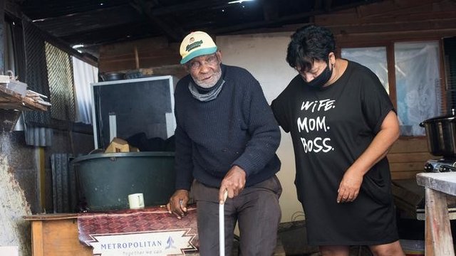 Fredie Blom (kiri) dibantu salah seorang putri dari istrinya ketika merayakan ulang tahun ke 116 di rumahnya di Delft, dekat Cape Town, 8 Mei 2020. Menurut 'Oupa' (kakek) Fredie dan kartu identitasnya, ia lahir pada tahun 1904 yang menjadikannya salah satu pria tertua di dunia. (RODGER BOSCH/AFP)