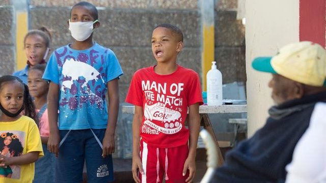 Anak-anak menyanyikan Selamat Ulang Tahun untuk Fredie Blom ketika merayakan ulang tahun ke 116 di rumahnya di Delft, dekat Cape Town, 8 Mei 2020. Menurut 'Oupa' (kakek) Fredie dan kartu identitasnya, ia lahir pada tahun 1904 yang menjadikannya salah satu pria tertua di dunia. (RODGER BOSCH/AFP)