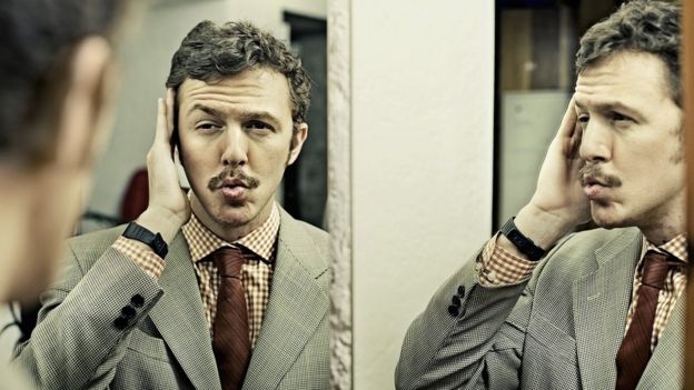 105604347_1a رجل ينظر بشغف إلى صورته في المرآة