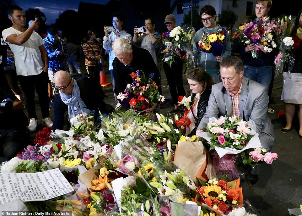11075914-6816537-image-a-7_1552747109371 Members of the community move flowers closer to one of the mosques as part of a vigil after the attack yesterday
