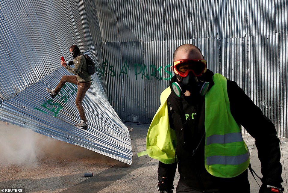 11077812-6816815-image-a-64_1552751981579 A protester wearing a yellow vest walks in front of demolished metal fencing during a demonstration by the "yellow vests" movement in Paris today