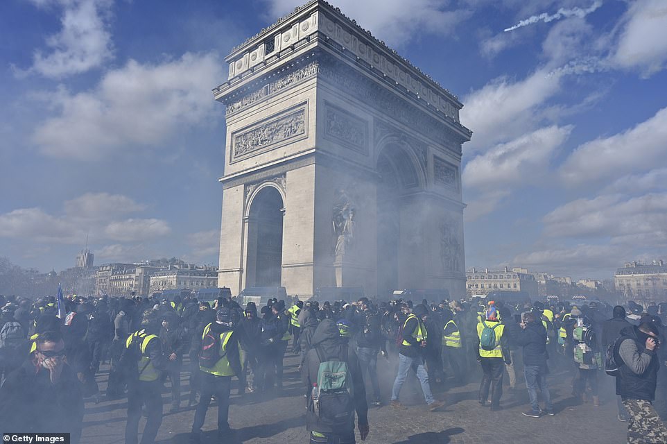 11077842-6816815-image-a-83_1552752116225 Protesters cover their faces and disperse momentarily after tear gas is fired into the crowd near Champs Elysees