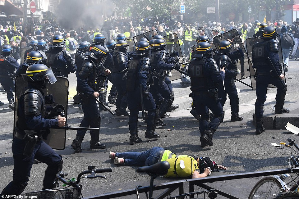 A protester lies on the ground during clashes with police today in Paris, as thousands of "Yellow Vest" (Gilets Jaunes) protesters took to the streets a 23rd week of anti-government marches.