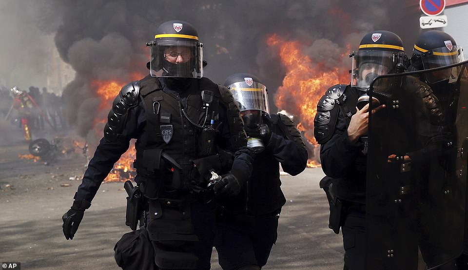 Police walk among burning vehicles during a yellow vest demonstration in Paris
