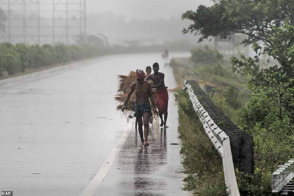 13038562-6988125-rush_for_safety_villagers_look_to_take_cover_on_a_road_on_the_ou-a-34_1556880886104 Rush for safety: Villagers look to take cover on a road on the outskirts of Puri as the cyclone hits amid fears it will cause a deadly storm surge