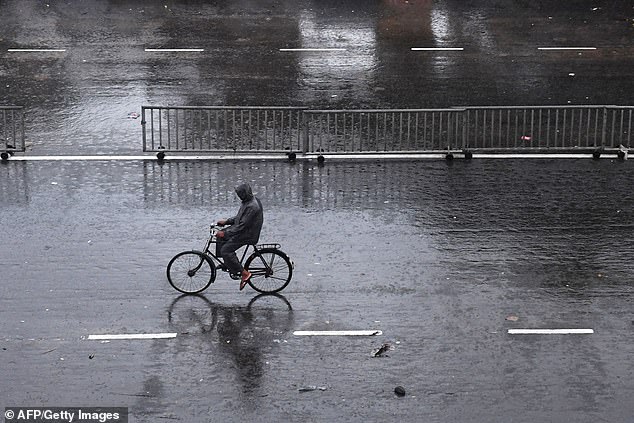 13043258-6988125-image-a-32_1556876579606 Lonely road: An Indian commuter cycles down a nearly deserted road in Puri in the eastern Indian state of Odisha early on Friday morning