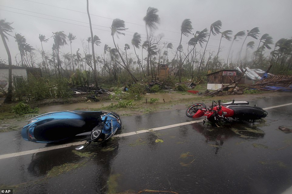 13049866-6988125-image-a-19_1556895758430 Knocked down: Motorcycles lie on a street in Puri district with trees blowing furiously in the background in Puri district today