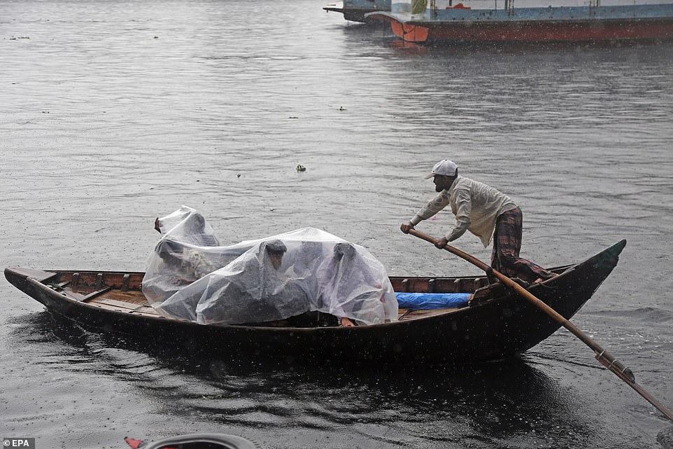 13049870-6988125-image-a-11_1556890597625 Bangladeshi passengers cover themselves with a plastic sheet as they cross the Buriganga River by boat during a rainy day in Dhaka