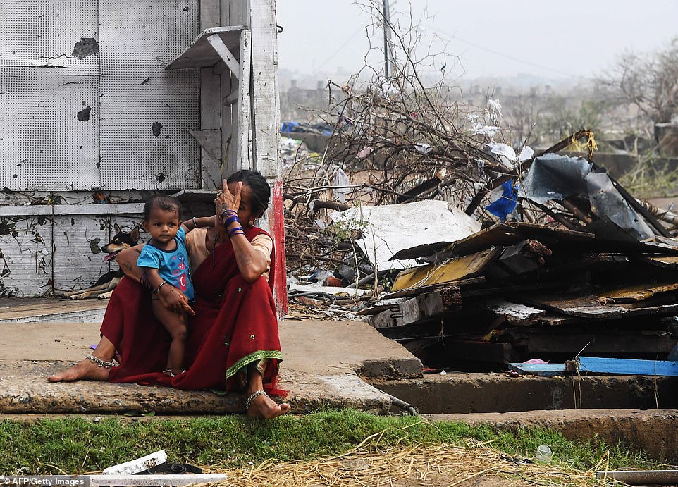 13077732-6991719-image-a-1_1556954465561 An Indian woman sits with her child next to storm-damaged buildings in Puri in the eastern Indian state of Odisha today after Cyclone Fani swept through the area