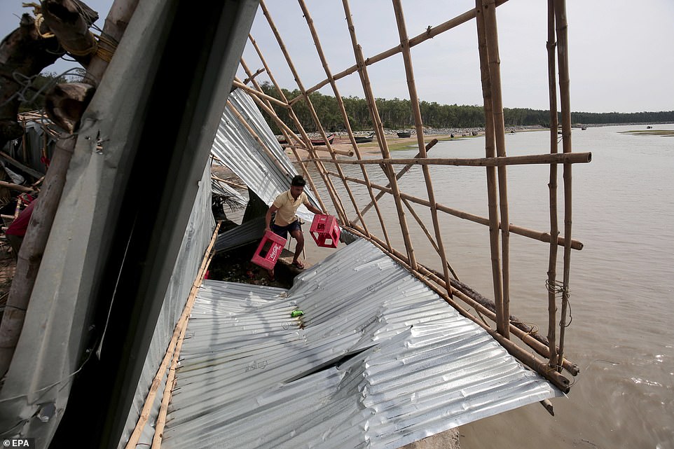13077776-6991719-image-a-17_1556954550601 An Indian man removes belongings from his food stall that was damaged after Cyclone Fani hit the town of Digha in West Midnapore district, West Bengal, India, today