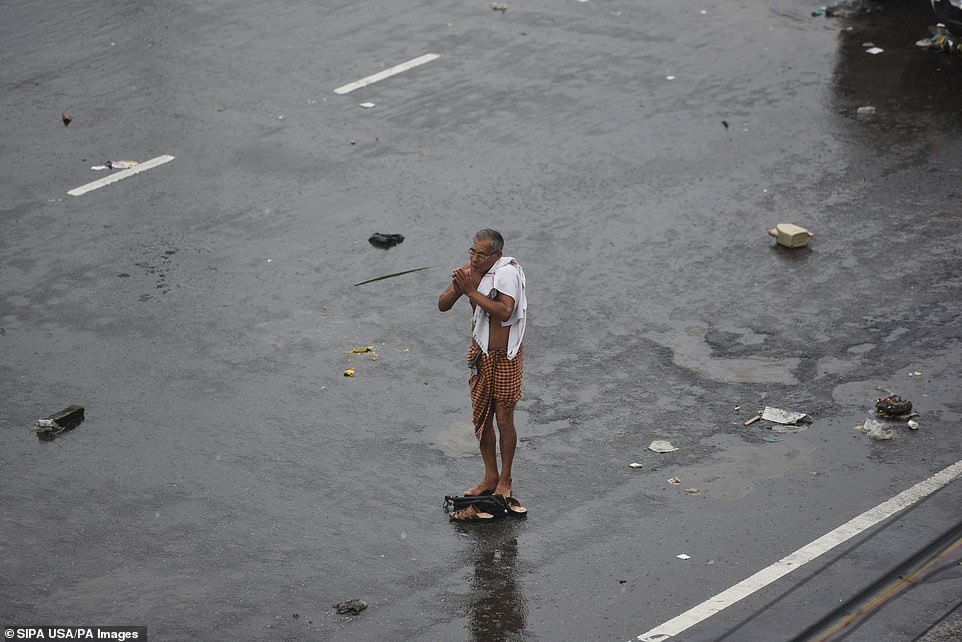 13077952-6991719-image-a-36_1556954696937 A man folds his hands in prayer as cyclone Fani hits the coast, on May 3, 2019 in Puri, India