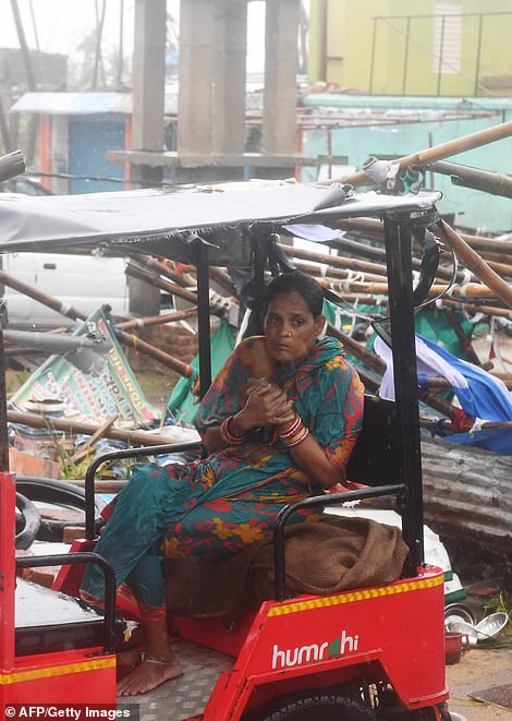 13077974-6991719-image-a-41_1556954713141 An Indian resident sits on an electric rickshaw next to a damaged structure
