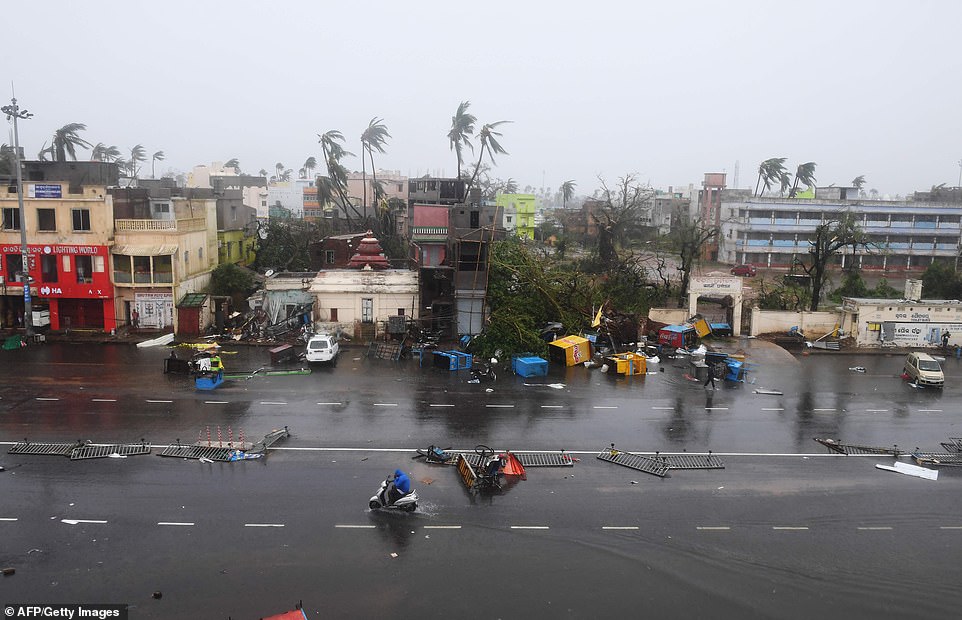 13077992-6991719-image-a-48_1556954769081 Indian residents ride along a road next to damaged trees. The storm sent coconut trees flying, blew away food stands and cut off power and water