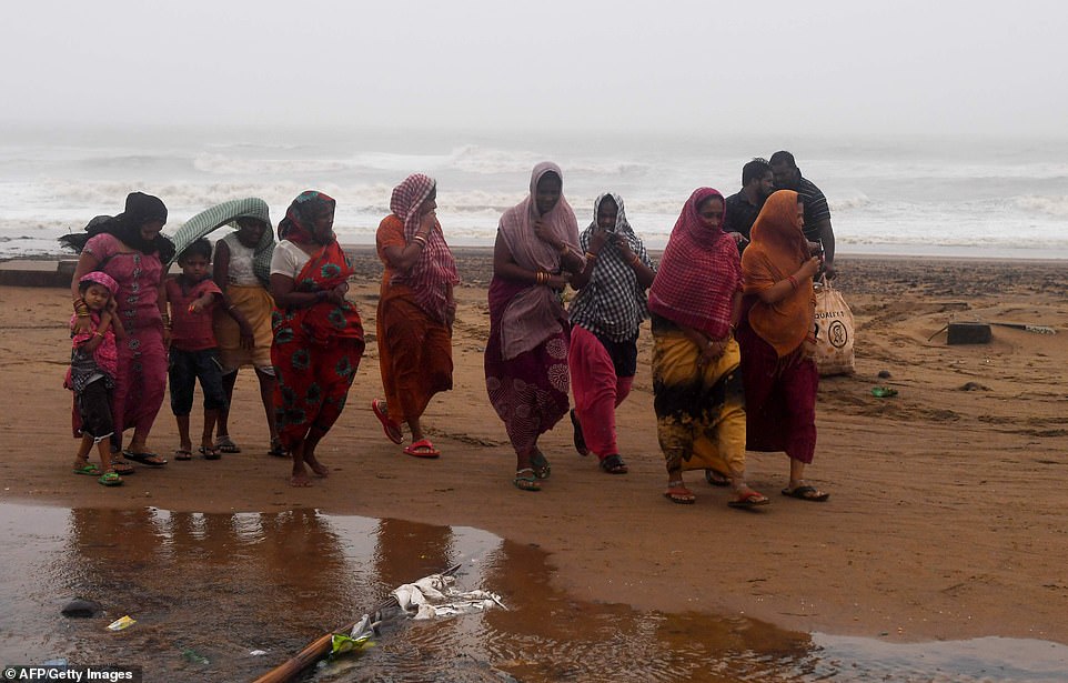 13078014-6991719-image-a-54_1556954827351 Indian residents walk along a beach after Cyclone Fani hits Puri, in the eastern Indian state of Odisha on Friday