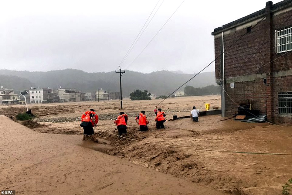 14689318-7132619-image-a-32_1560345407466 Video footage released by Xinhua today shows a team of rescuers struggling to lift several stranded residents out of raging, muddy waters in Heyuan, Guangdong province