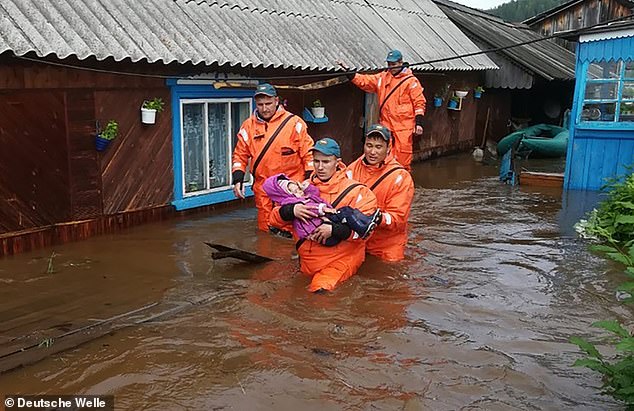 15440616-7197469-image-a-42_1561890703316 Rescuers evacuating a child from a flooded residential building. So far five people have been killed in the flooding
