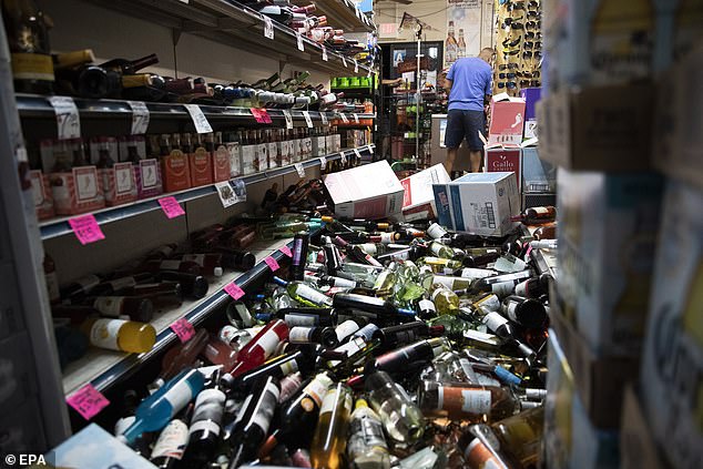 15704718-7219443-image-a-20_1562415693356 A man walks in the middle of fallen and broken bottles in a gas station and liquor store the 178 after an earthquake in Ridgecrest