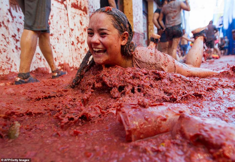17792502-7403445-image-a-79_1567005560521 A smiling and clearly delighted young woman dives into a thick pile of tomato pulp during this year's edition of the annual festival