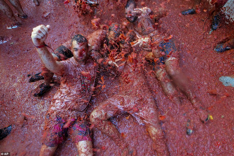 17792624-7403445-image-a-102_1567005655775 Their eyes screwed shut against the barrage of tomatoes being flung at them, a group of friends lay on the ground during the event