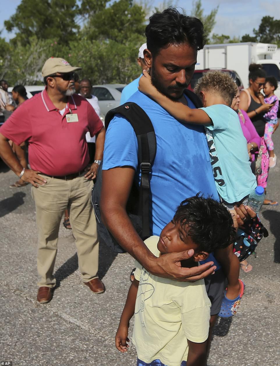Steven Turnquest comforts his sons Leslie and Kile as they wait for assistance at the airport in Nassau, Bahamas, on Thursday