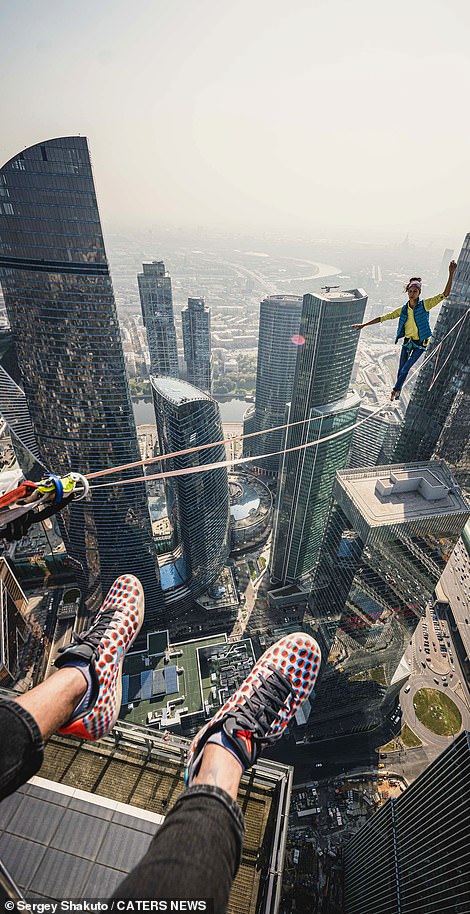 18337158-7451443-image-m-54_1568193865162 One of the athletes dangles his feet over the edge of the skyscraper as another walks along the slack line