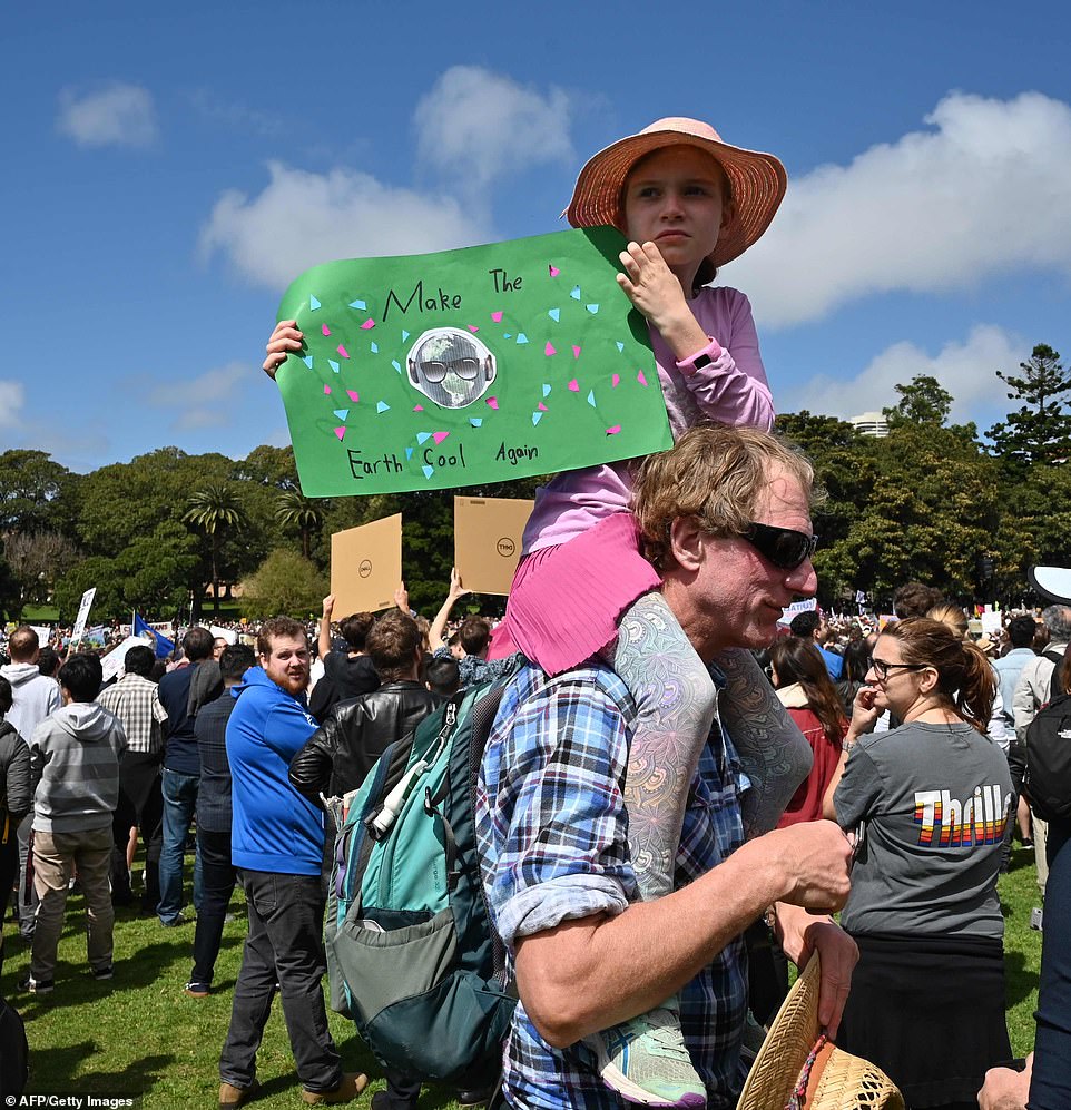 18702358-7484625-image-a-77_1568952934261 A girl sits on her dad's shoulders as she holds up a sign which read: 'Make the Earth cool again'