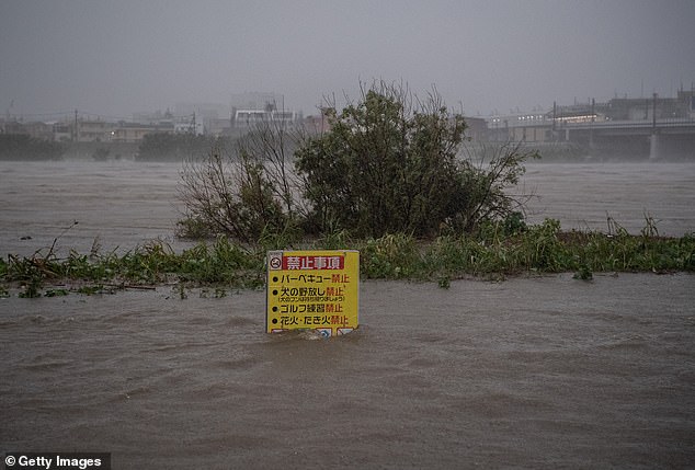 19624938-7565683-image-a-8_1570879644302 A sign is partially submerged as the Tama River floods during Typhoon Hagibis