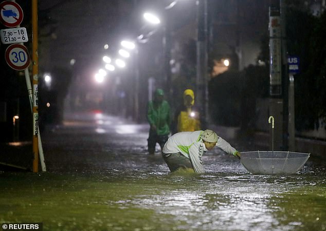 19628110-7565683-image-a-82_1570890359291 Pedestrians were seen wading through flooded roads as the powerful storm took hold in Japan