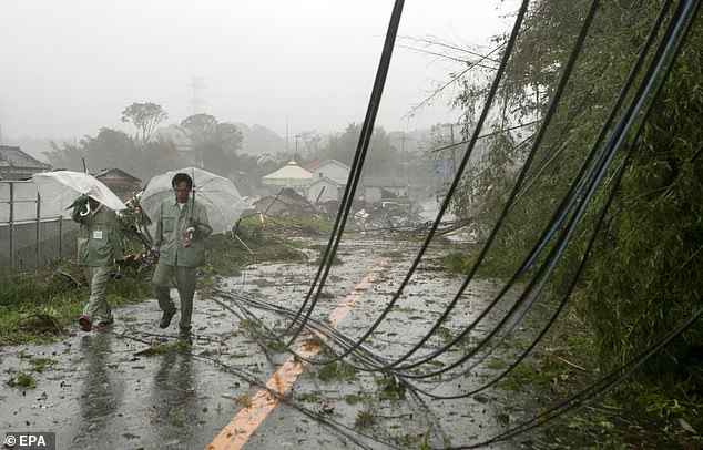 19628116-7565683-image-a-79_1570890175097 Two people walk through cables which fell on the road in Ichihara, Chiba Prefecture