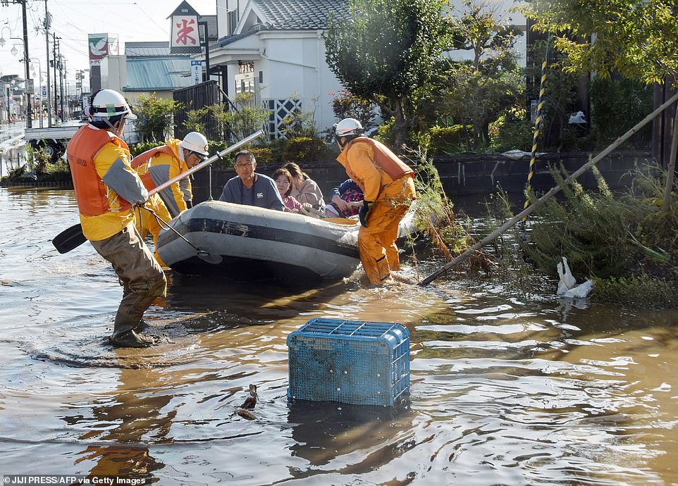 19651574-7567507-image-a-49_1570962123590 Fire department workers evacuate residents today using a rubber dinghy from a flooded area in Date, Fukushima prefecture
