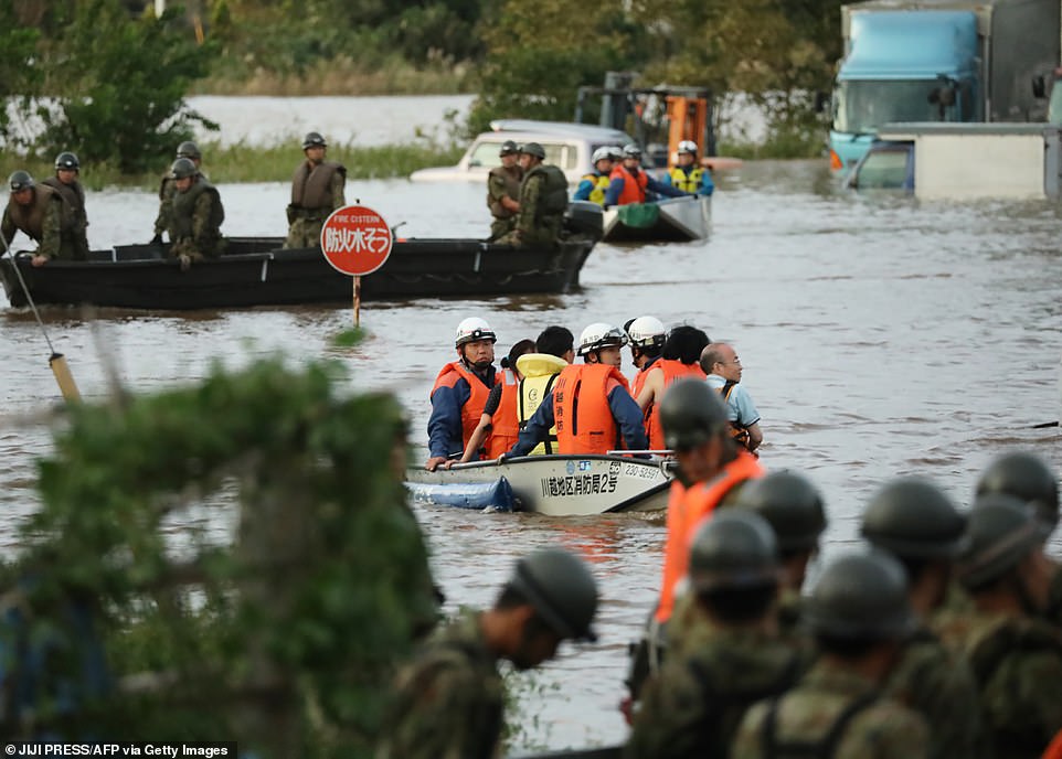19651576-7567507-image-a-54_1570962284022 Fire department workers are seen evacuating residents while soldiers take part in rescue efforts in a flooded area in Kawagoe, Saitama prefecture on Sunday