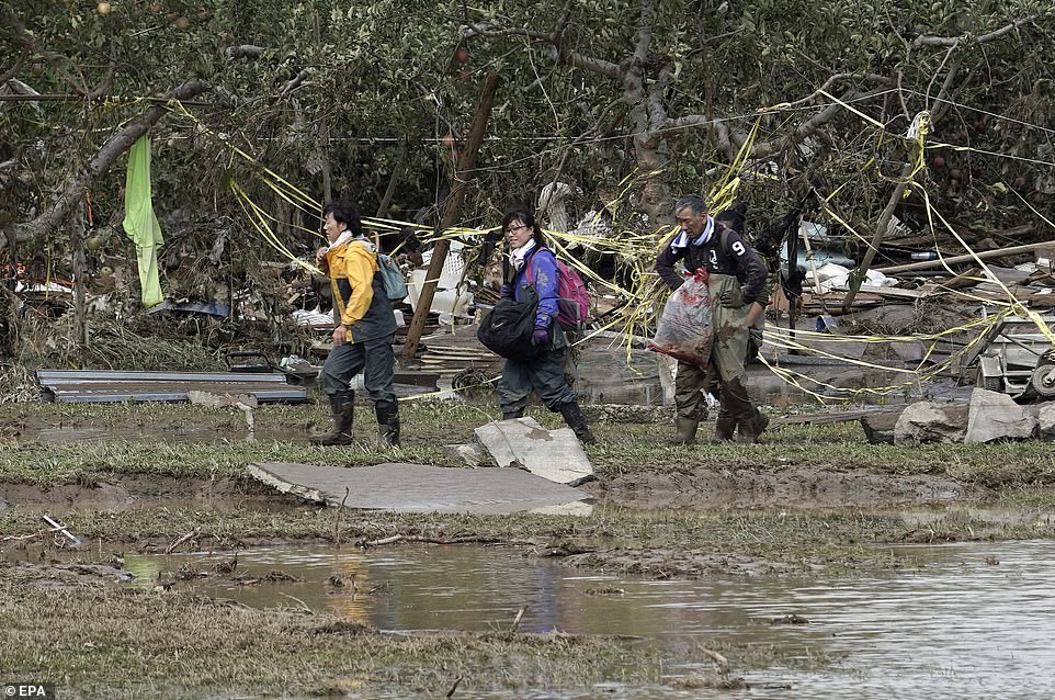 19680296-7570251-image-a-37_1571038552931 Residents bring out their belongings from their houses in the Hoyasu area, flooded and devastated by Typhoon Hagibis, in Nagano, Nagano Prefecture, central Japan