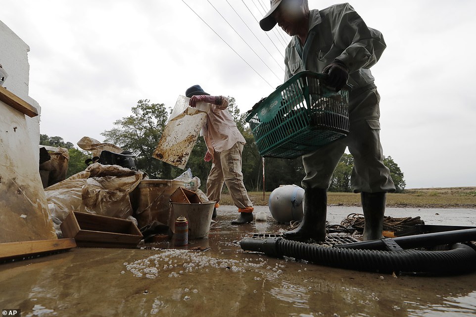 19680314-7570251-image-a-29_1571038302408 Residents Kazuo Saito (right) and Sumiko Saito clean up their home today in Kawagoe City, Japan, after the devastation of the typhoon