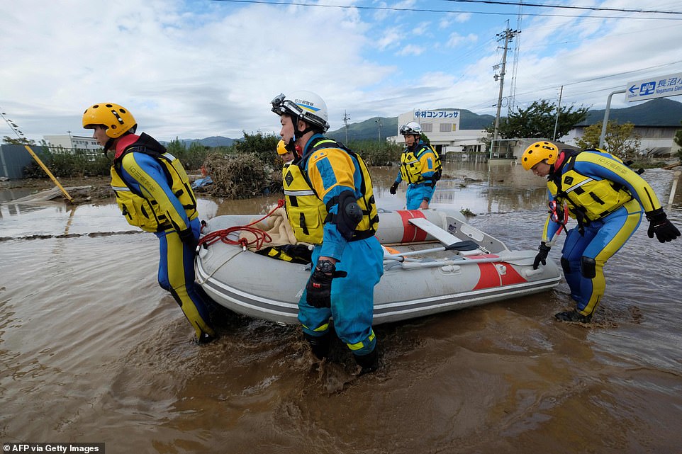 19680326-7570251-image-a-28_1571038257180 Rescuers carry out a rubber dinghy from the water during search and rescue operations in the aftermath of Typhoon Hagibis in Nagano