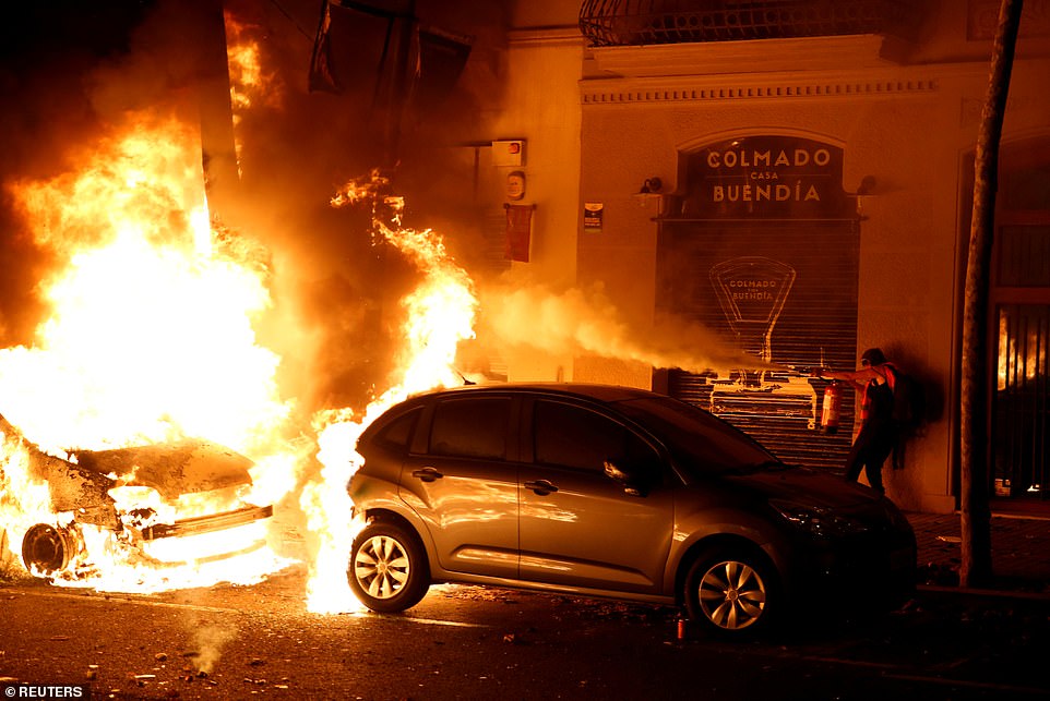 19813508-0-image-a-109_1571270067441 A person extinguishes a burning car during the latest bad-tempered night of protests in the Catalonia region following Monday's ruling