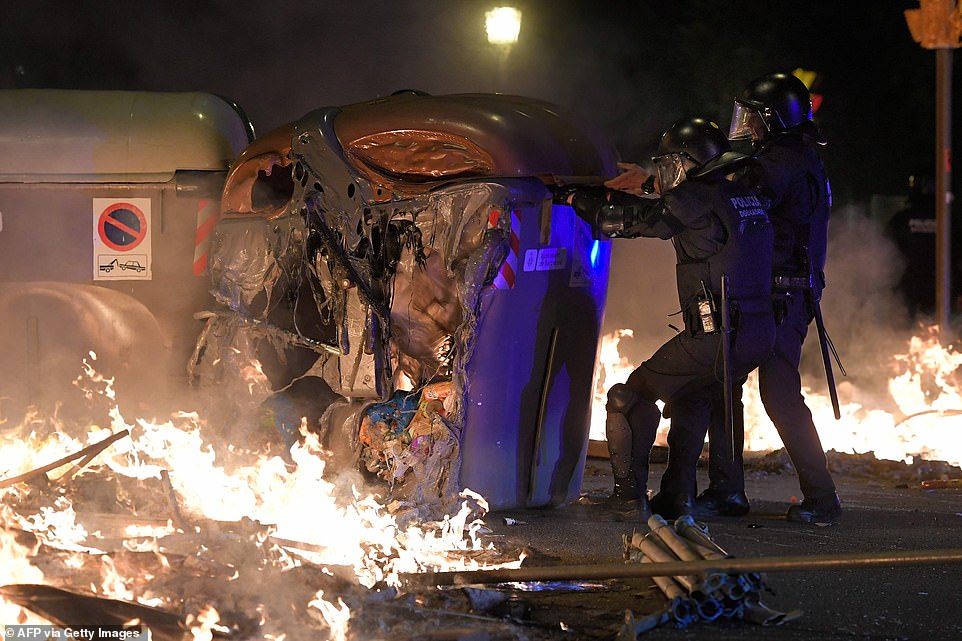 19813624-0-image-a-59_1571269639597 Catalan anti-riot police officers pull a melted skip used as a barricade by protesters during a demonstration in Barcelona on Wednesday night