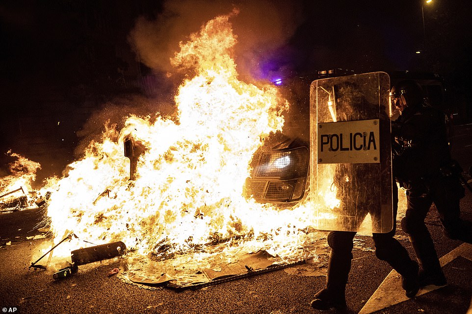 19815254-7581995-image-a-134_1571272325682 Policemen run as a police van drives over a burning barricade during clashes between protesters and police in Barcelona, Spain, Wednesday