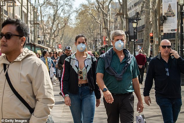 25891352-8105339-image-a-31_1584026954880 Spanish hotels have received n new bookings due to the growing threat of coronavirus, with experts claiming the virus is rapidly spreading across the country like 'a tsunami' (Pictured: Tourists wear protective masks on the streets of Barcelona)