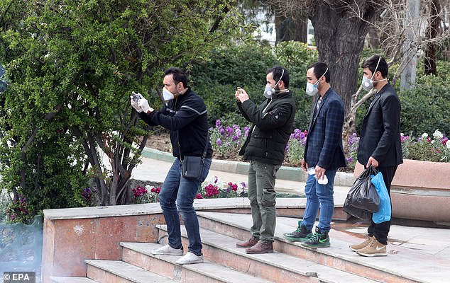 25940832-8109981-image-a-182_1584117463630 Iranians wearing face masks take pictures of firefighters disinfecting the streets in an effort to stop the wild spread of coronavirus
