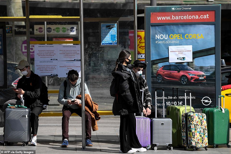 25995074-8114189-image-a-38_1584285189274 Tourists wearing face masks wait for the airport bus in Barcelona on March 15, 2020. France and Spain are the latest European nations to severely curtail people's movements
