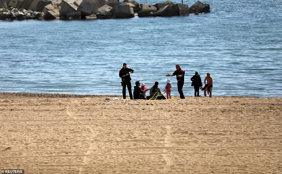 25996588-8114189-image-a-46_1584286348938 Police officers tell a family to leave the Barceloneta beach area amidst concerns over Spain's coronavirus outbreak, in Barcelona, today