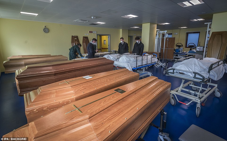 26115068-8123307-image-m-13_1584531603889 Hospital workers prepare coffins at the Ponte San Pietro hospital in Bergamo on Tuesday, in the province of Lombardy which has been the worst-affected region of Italy