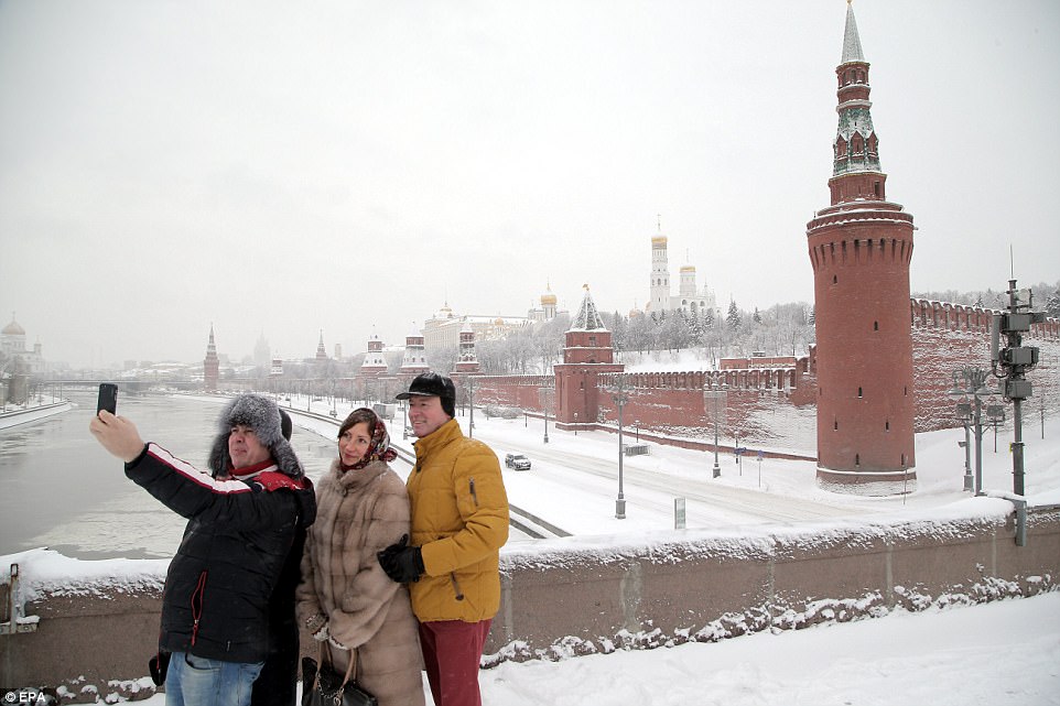 Tourists snap a selfie in front of the Kremlin as freezing conditions brought chaos to the capital, leaving thousands without power 