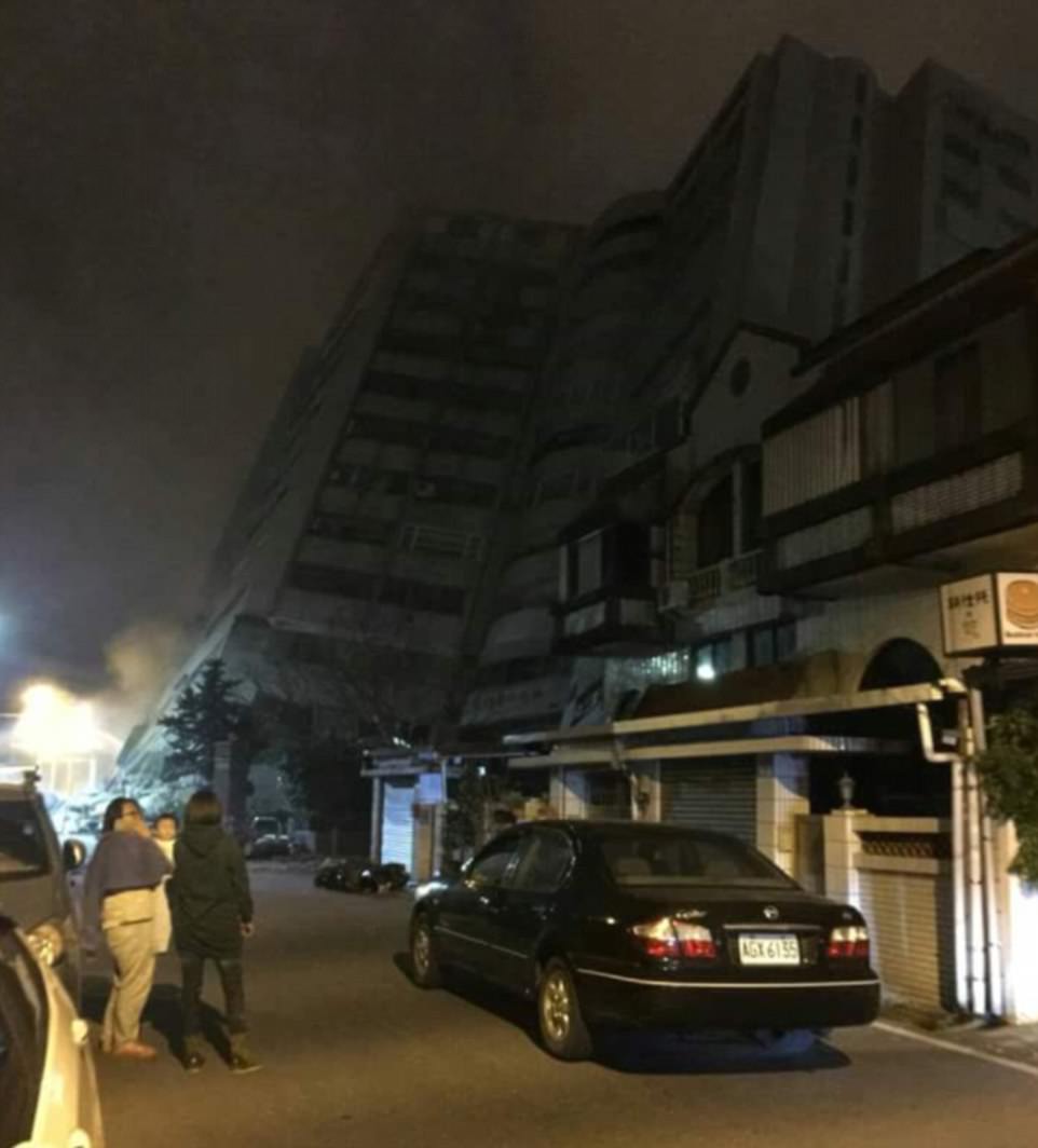 Witnesses stand on the street outside the collapsing hotel, while other lower buildings seem undamaged by the earthquake