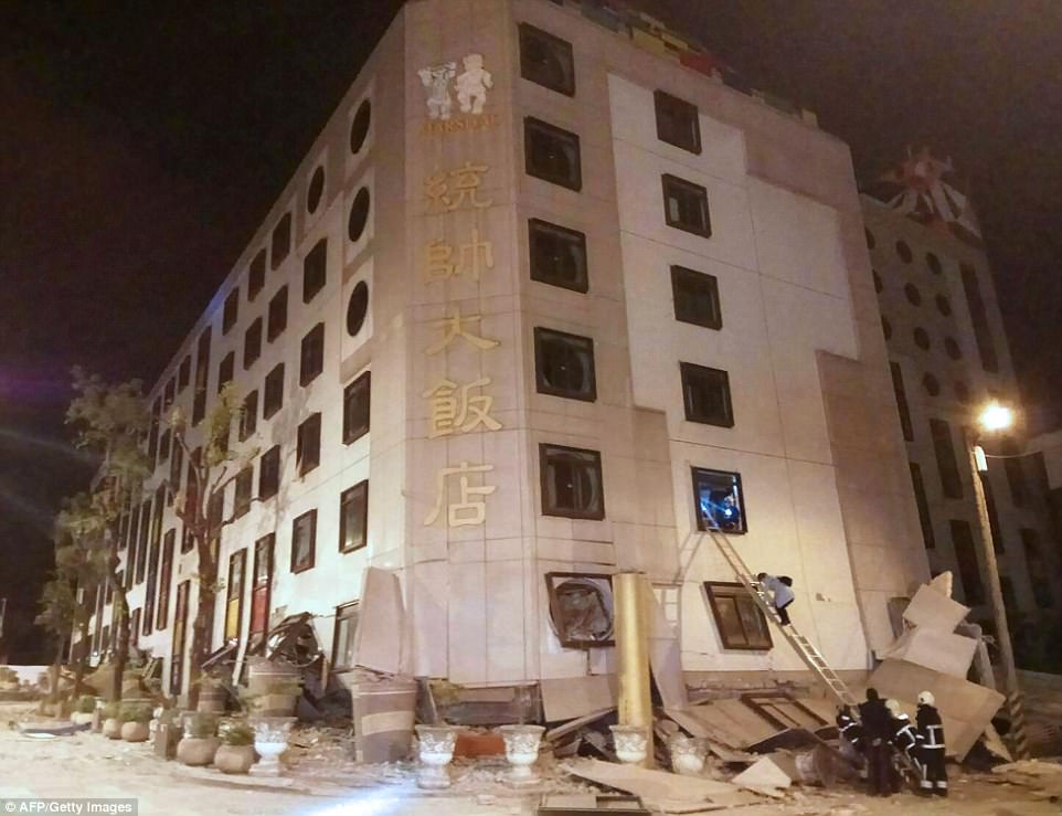 Rescue workers are seen using a ladder to help someone climb from a window as they respond to the earthquake