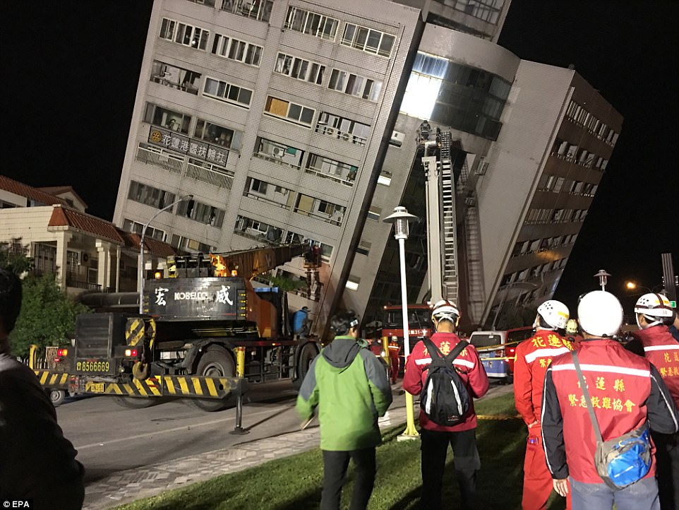 Emergency vehicles are pictured at the scene with the building in the background slanted at a precarious angle