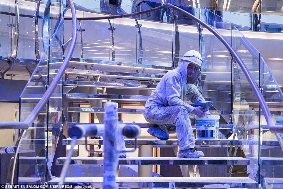 A construction worker applies the finishing touches to a glass and steel staircase 