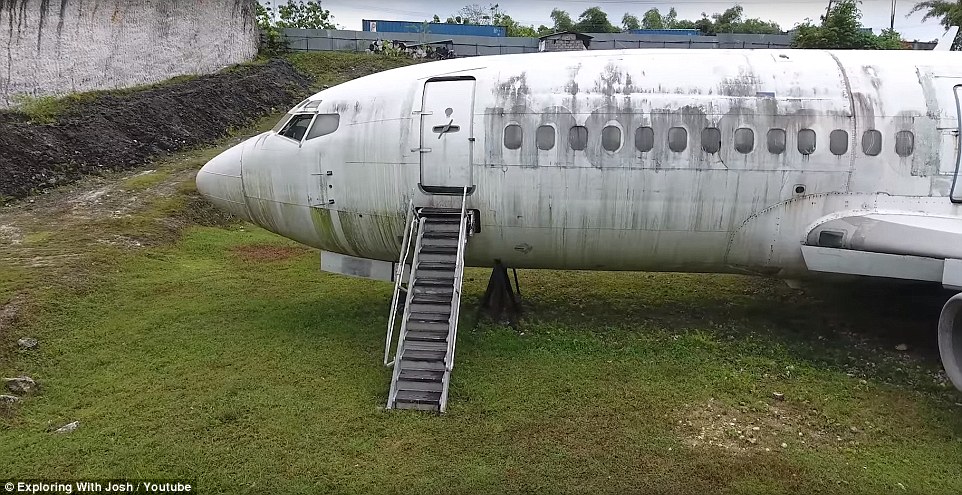 Surrounded by leafy trees, shipping containers and a hut, the plane rests in a large ditch just off the busy Raya Nusa Dua Selatan Highway